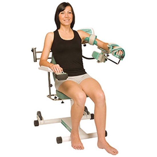 A woman in New York sits on a chair using an Anatomical Shoulder CPM machine for rehabilitation