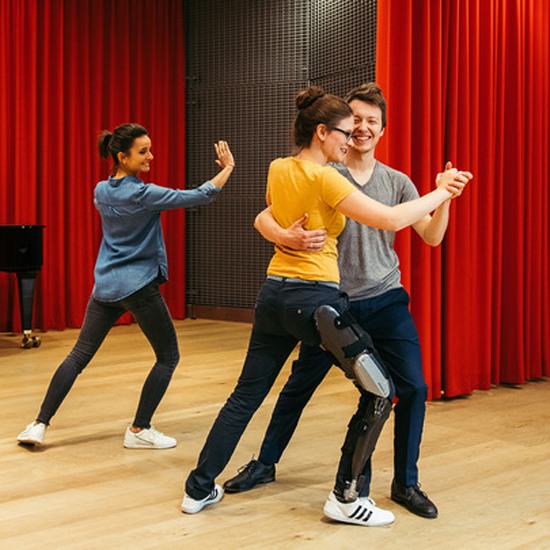 A lady wearing a C-Brace dancing with her trainer on the stage in New York and New Jersey