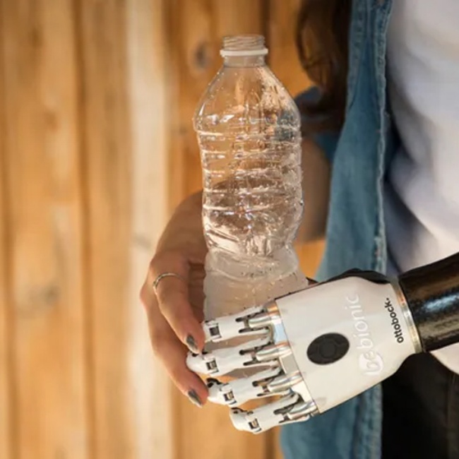 A woman holds a bottle with her upper limb prosthetic hand in New York, New Jersey, & Connecticut