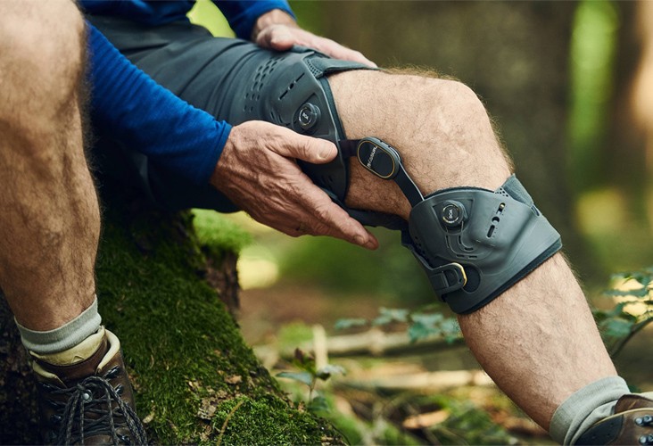 A Man Sitting on a Wooden Log Checking His Custom Brace in New York & New Jersey